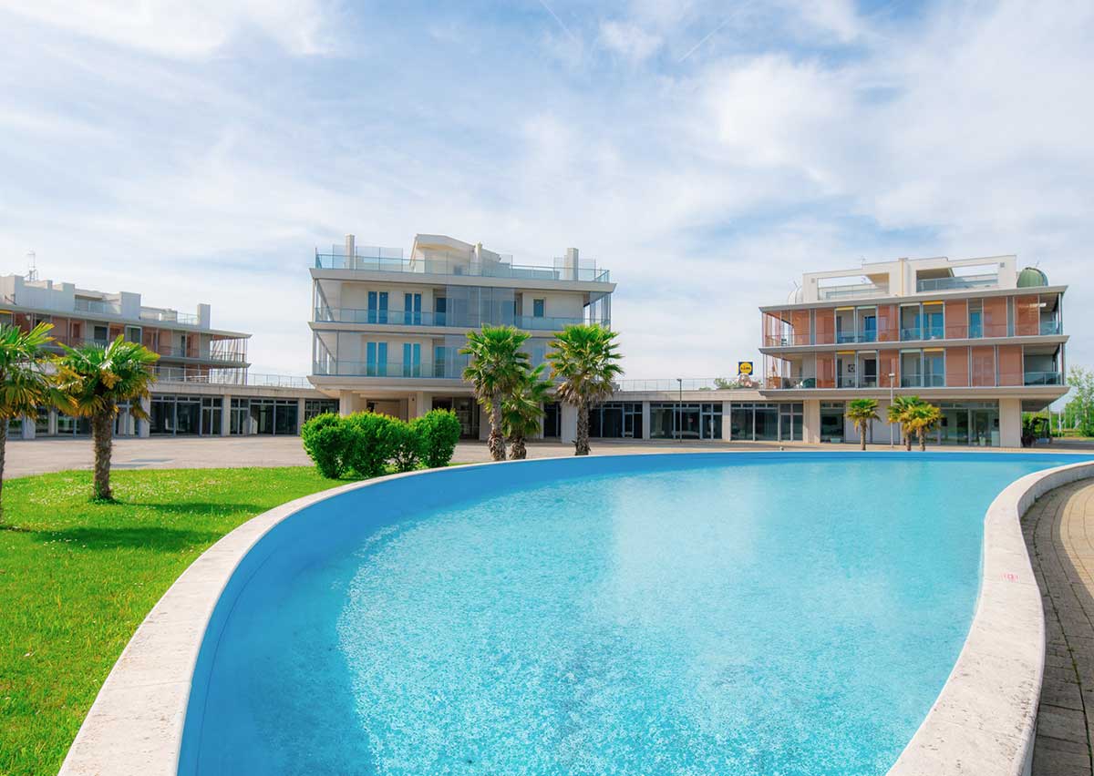 Valorizzazione immobiliare Isola Blu Jesolo: servizio fotografico di edificio, terrazze, viste e contesto urbano per sito, social e vendita.